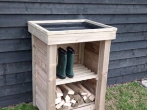 Handcrafted wooden planter with integrated log store by RA Garden Ideas. The top section can hold pots or plants, while the lower shelf provides space for boots, tools, or a bundle of logs.