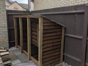8ft wooden deep log store in brown, shown from sharp angle, triple bay with featheredge cladding.