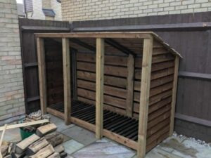 8ft deep log store with 930mm depth, triple bay design in brown finish, angled side view.