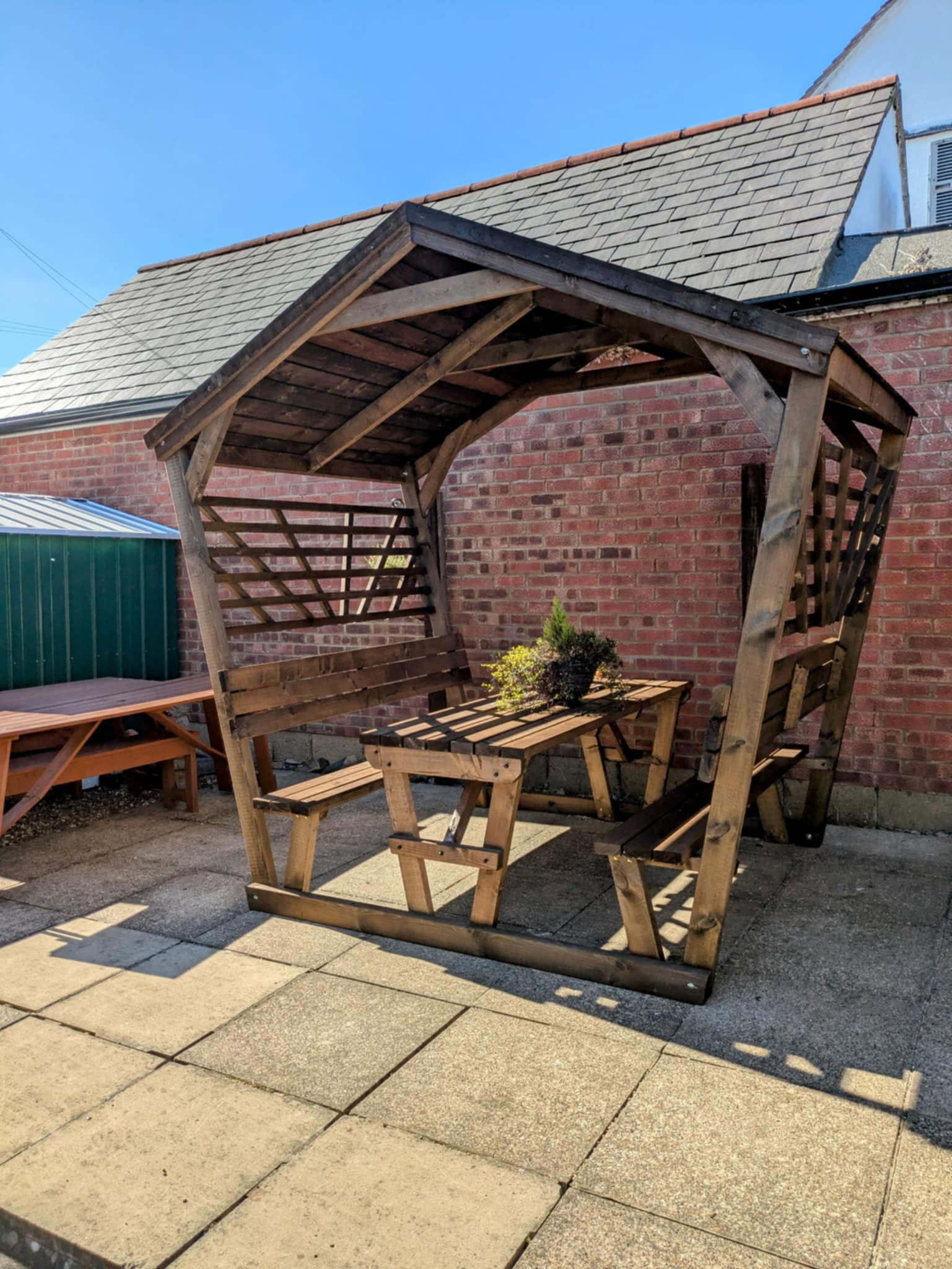Covered picnic pod with featheredge roof viewed from the side with fixed benches and table