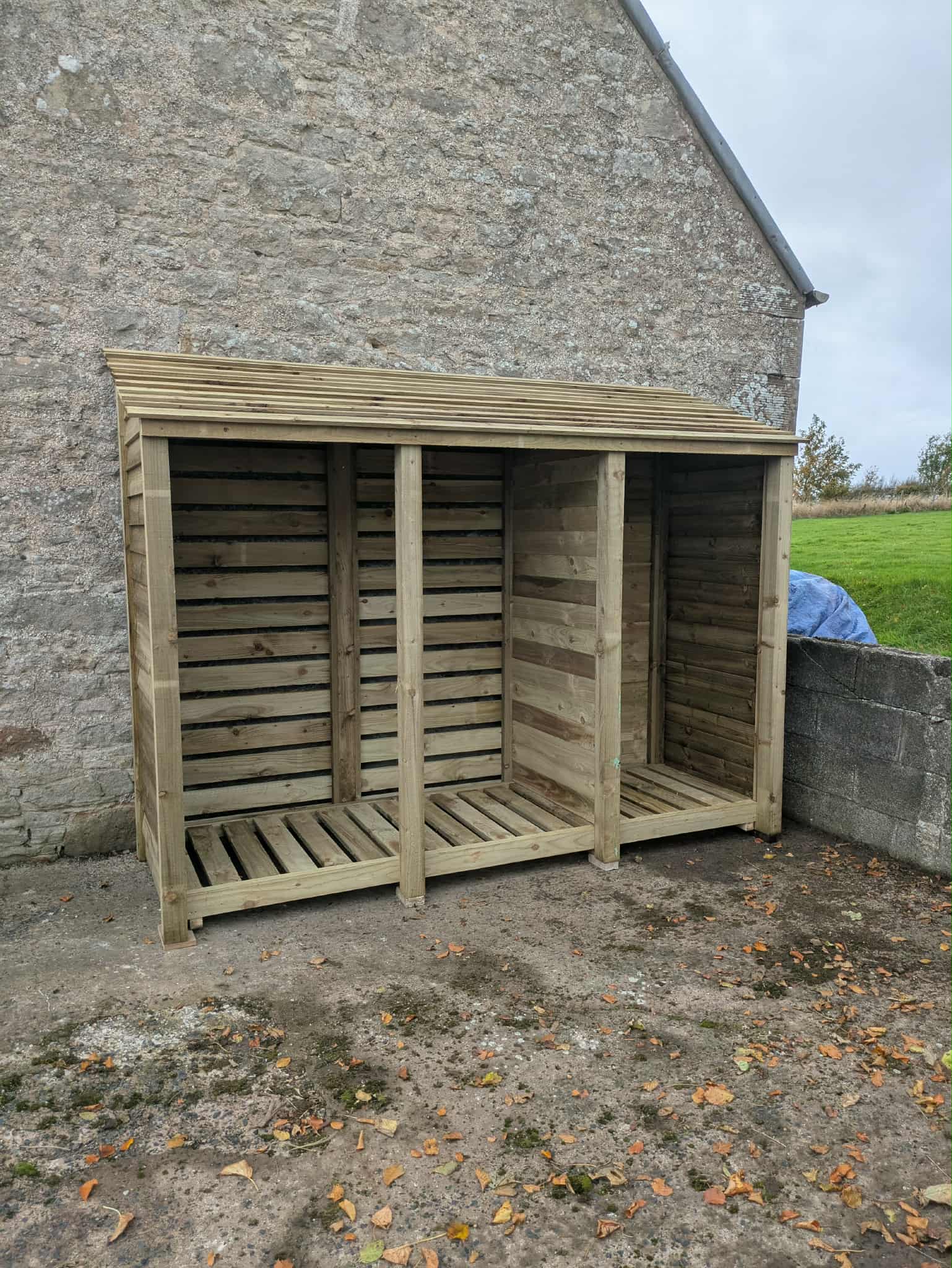 9ft deep log store with partition panel in green finish, 7ft tall